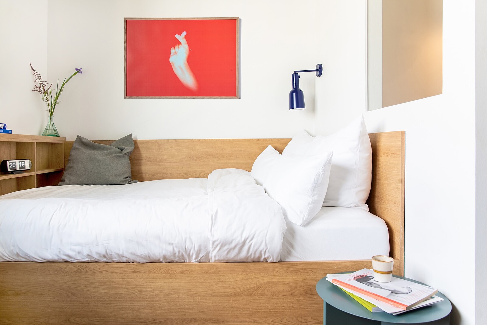 Komfortables Bett mit Beistelltisch und Bild an der Wand