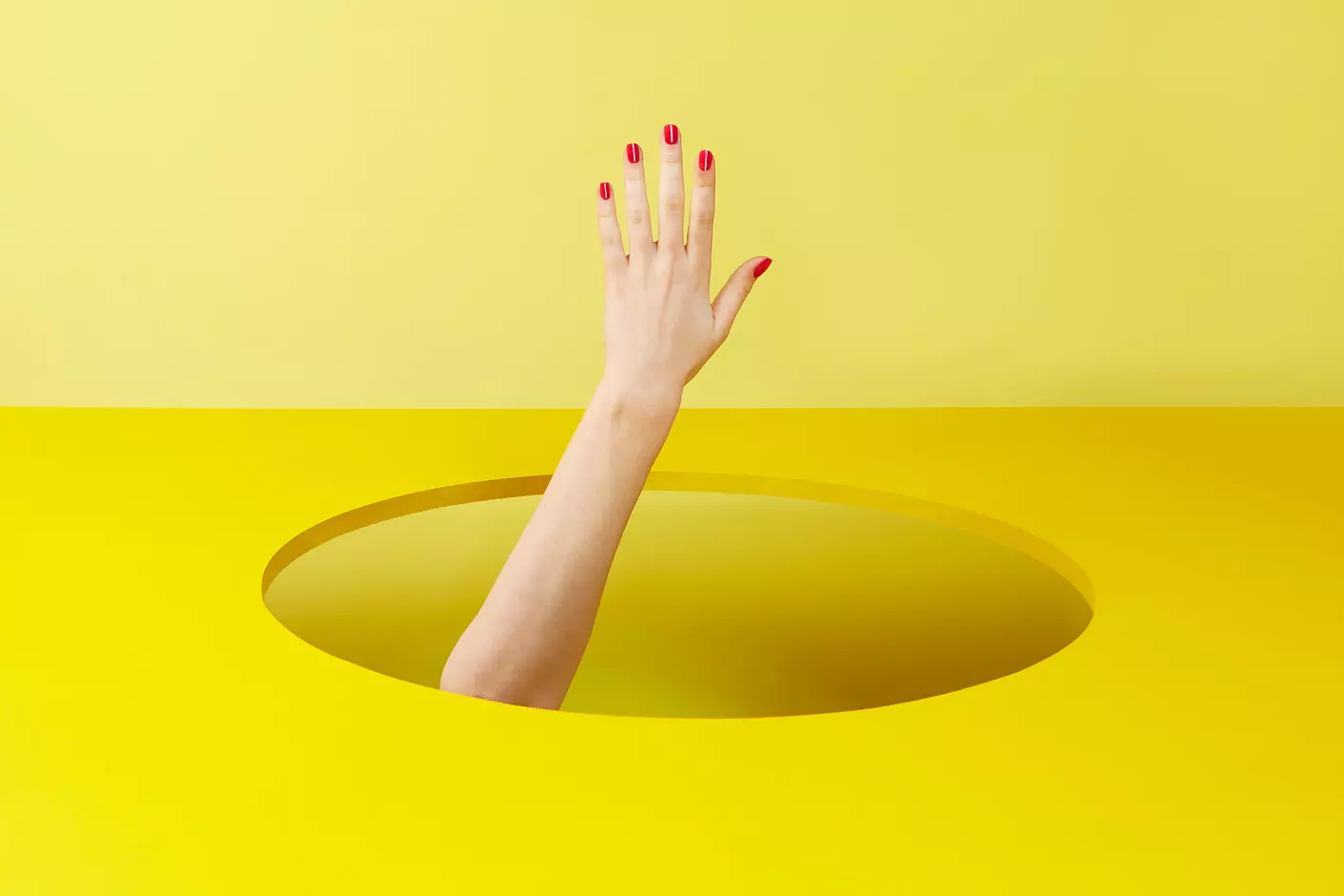 La mano de una señora asomando por un agujero en una mesa, como señal de la gran demanda de locales inmobiliarios