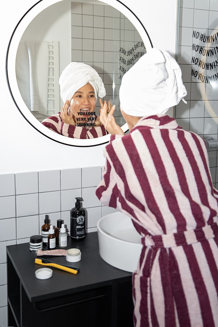 Frau schaut glücklich in den Spiegel